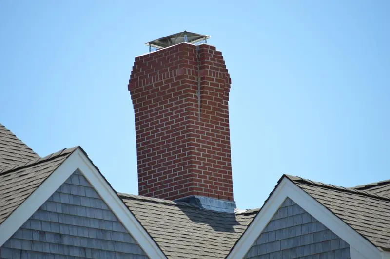 Brick chimney with metal flashing on a shingled roof