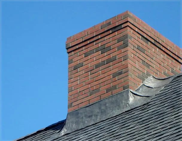 Brick chimney with copper pan flashing where it meets the roof