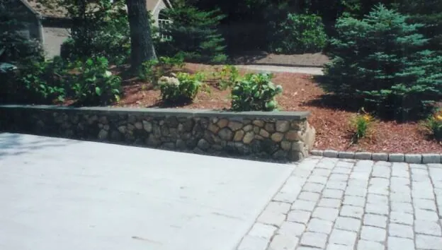 Cobblestone driveway apron and low stone wall