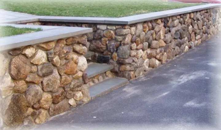 Fieldstone retaining wall with stone steps along a driveway