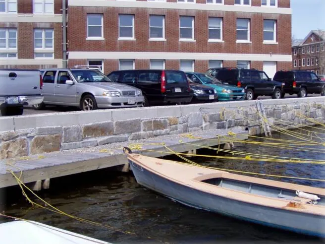 Granite seawall and dock with small boats at a harbor