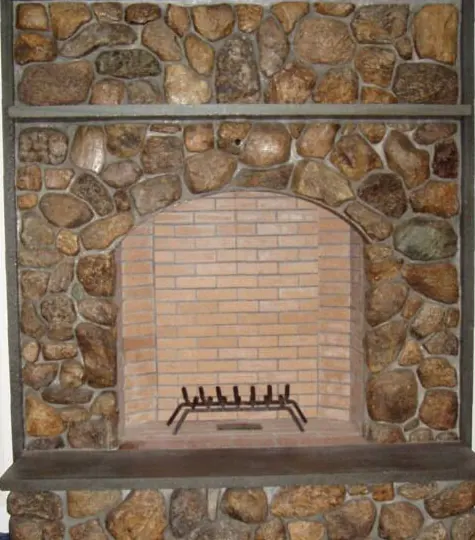 Fieldstone fireplace with an arched brick firebox built by Steve Kady Masonry