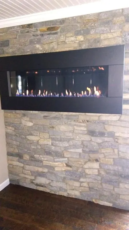 Modern linear gas fireplace set into a stacked stone wall