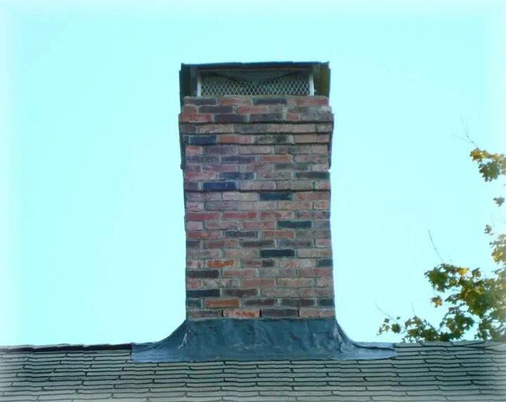 Weathered brick chimney against a clear sky
